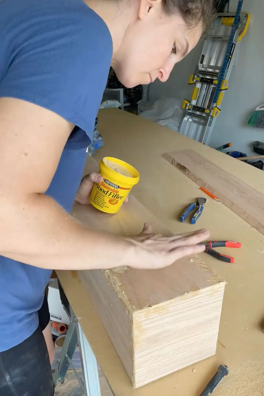 Filling gaps and nail holes with wood filler on a DIY fireplace mantel before sanding for a smooth finish.